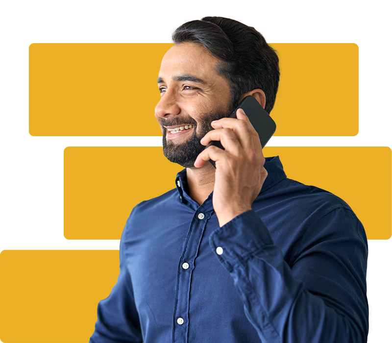 A smiling man an holding his cellphone to his ear.