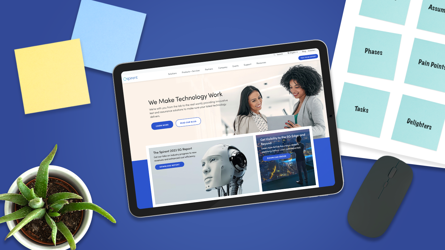 Flatlay with an iPad featuring the Spirent website on the display. The iPad is surrounded by sticky notes, a plant, and a computer mouse.